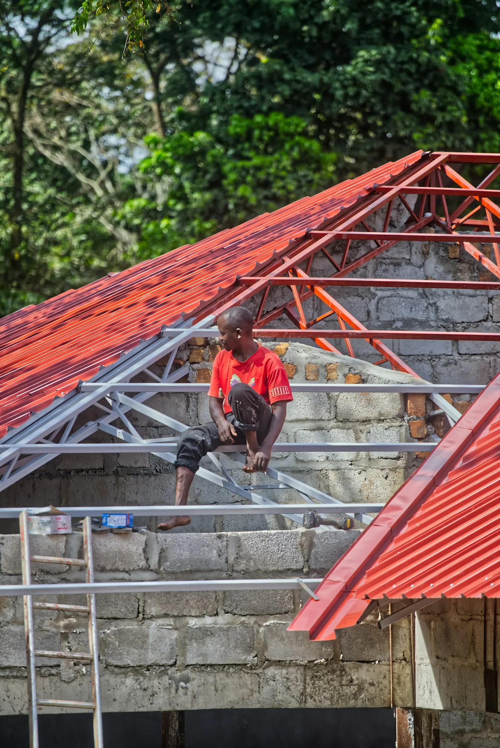 Pekerja memasang genteng metal merah baru pada rangka atap di Bantar Gebang