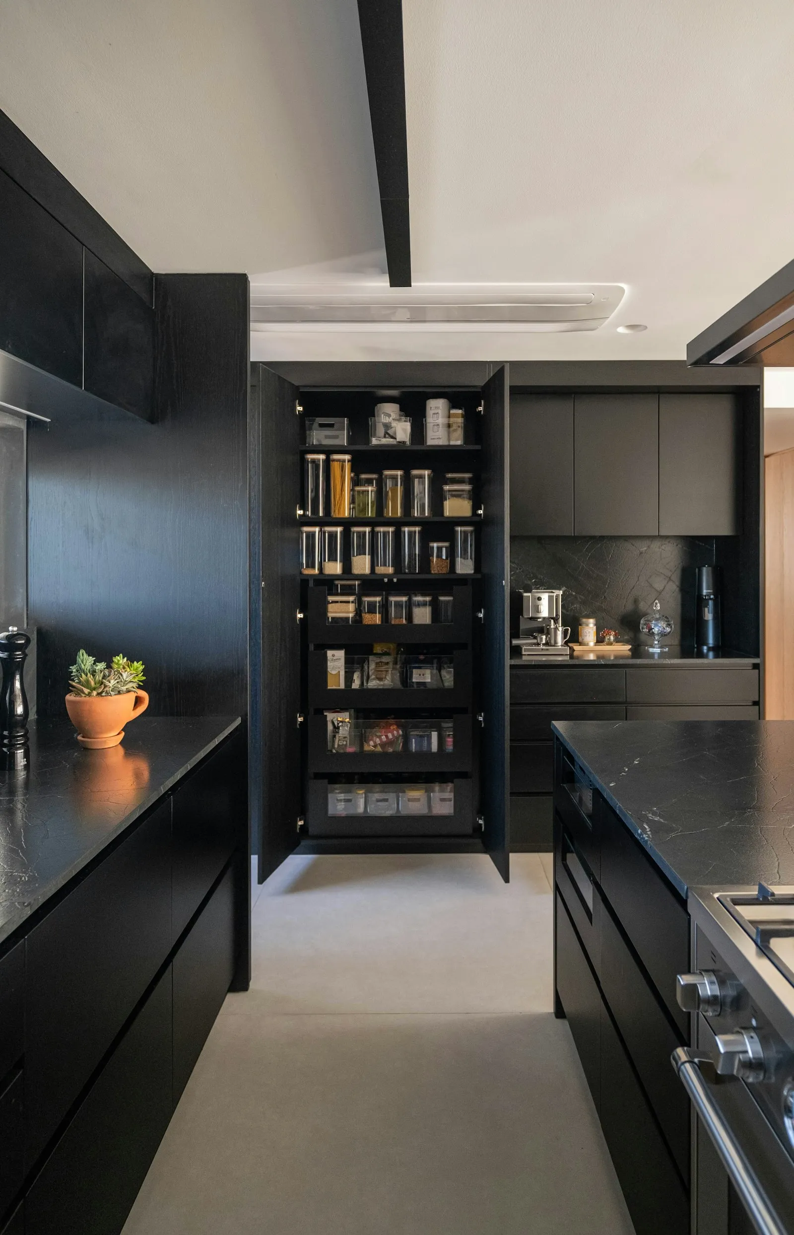 Dapur island bergaya modern dengan kabinet gelap dan pantry terorganisir