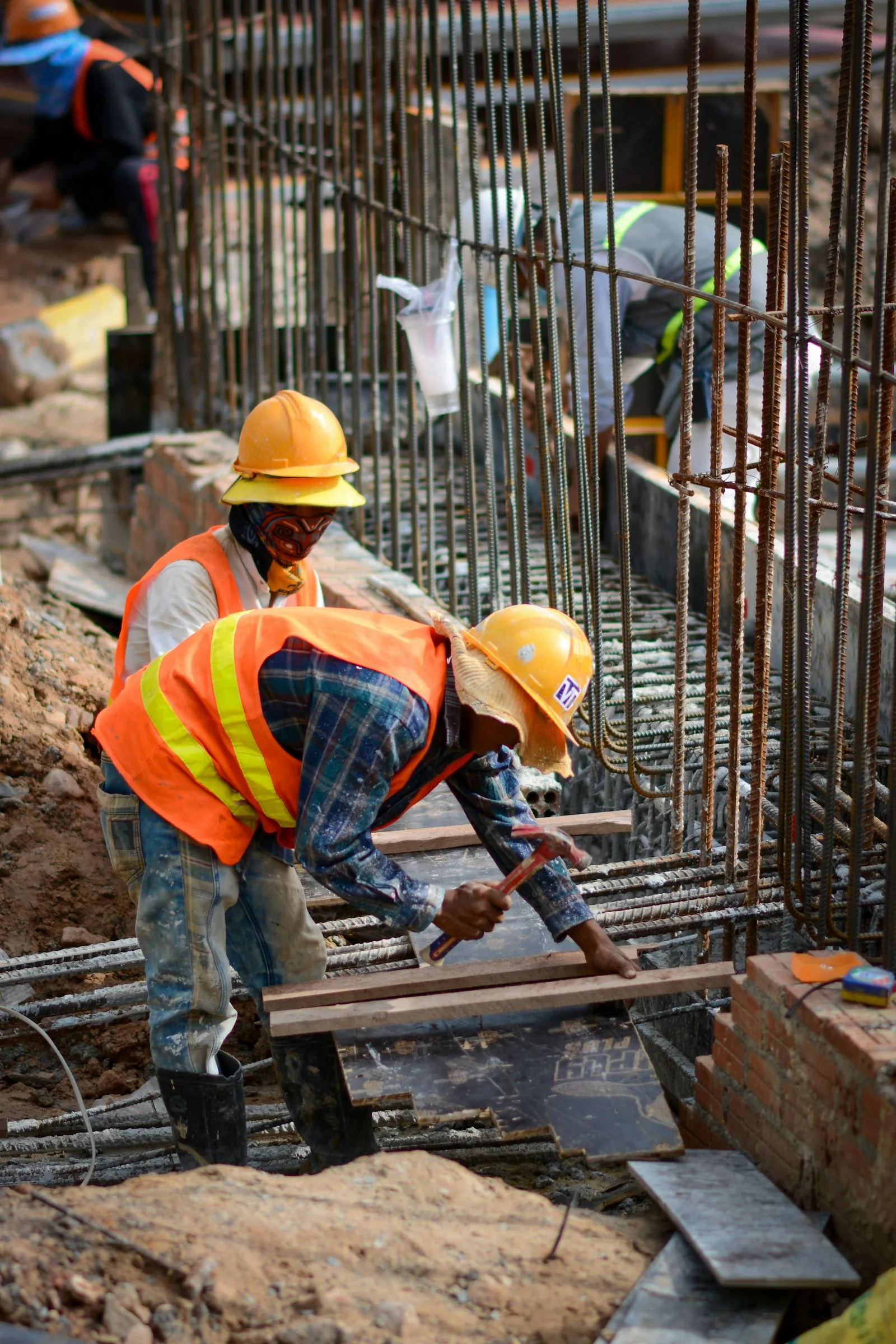 Dua pekerja konstruksi mengerjakan struktur beton bertulang di lokasi proyek